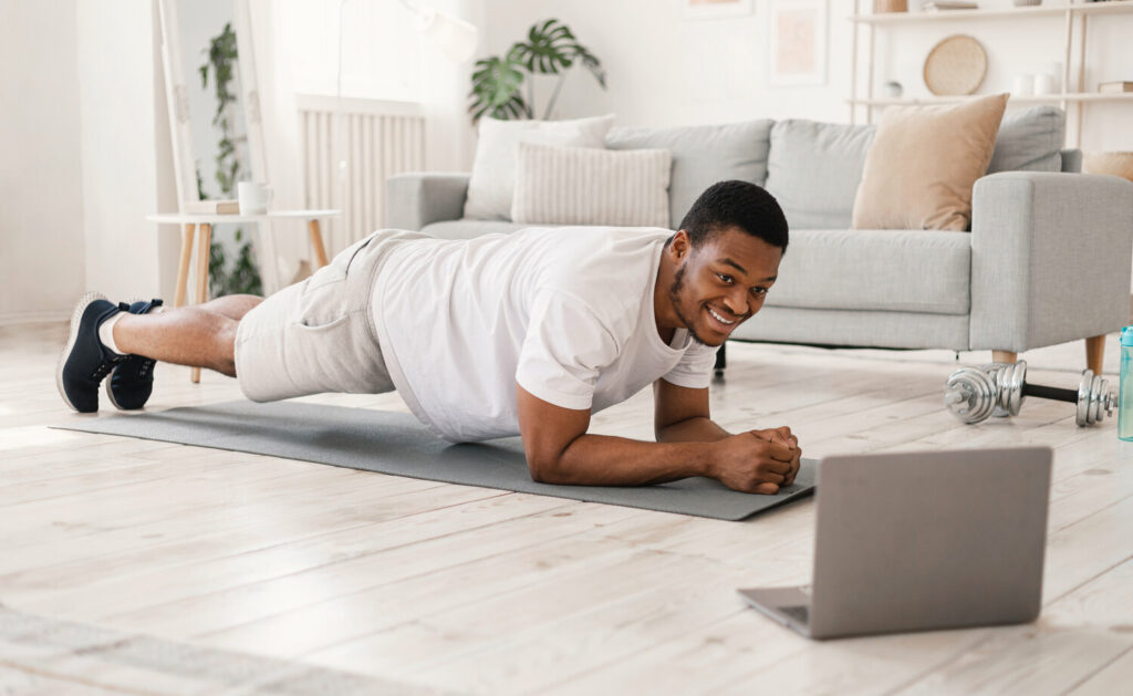 black man exercising doing plank exercise at lapto H8QBENY