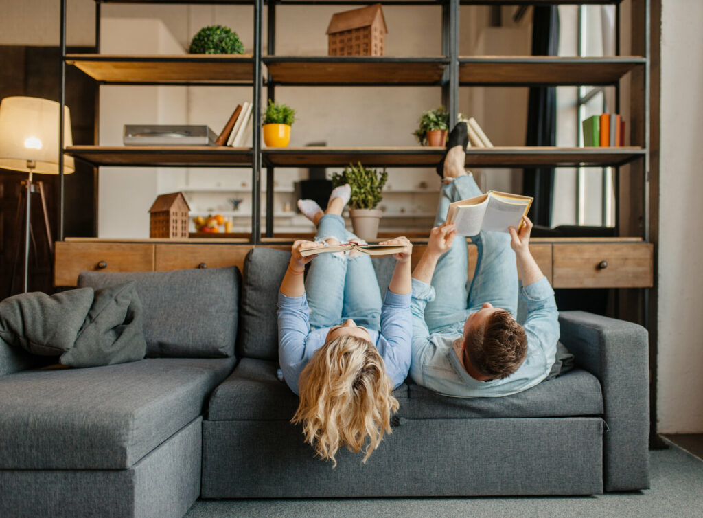 couple with books lying on the couch upside down XJVSD5R