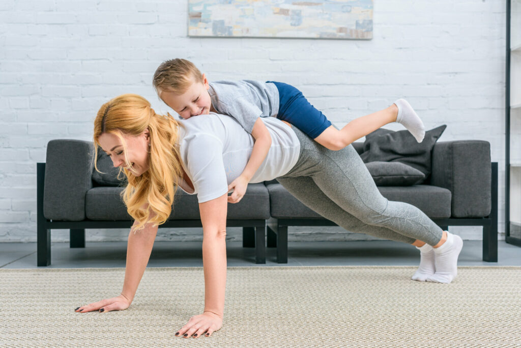 smiling mother doing plank with little boy on back XZ4XQ3S